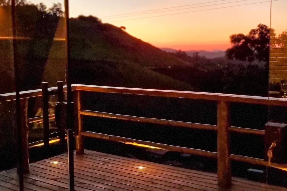 Deck do chalé com o pôr do sol atrás das montanhas