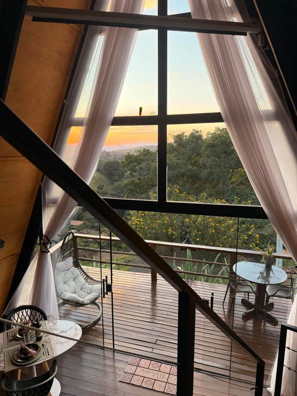 Cortinas abertas para o deck e o vale ao entardecer